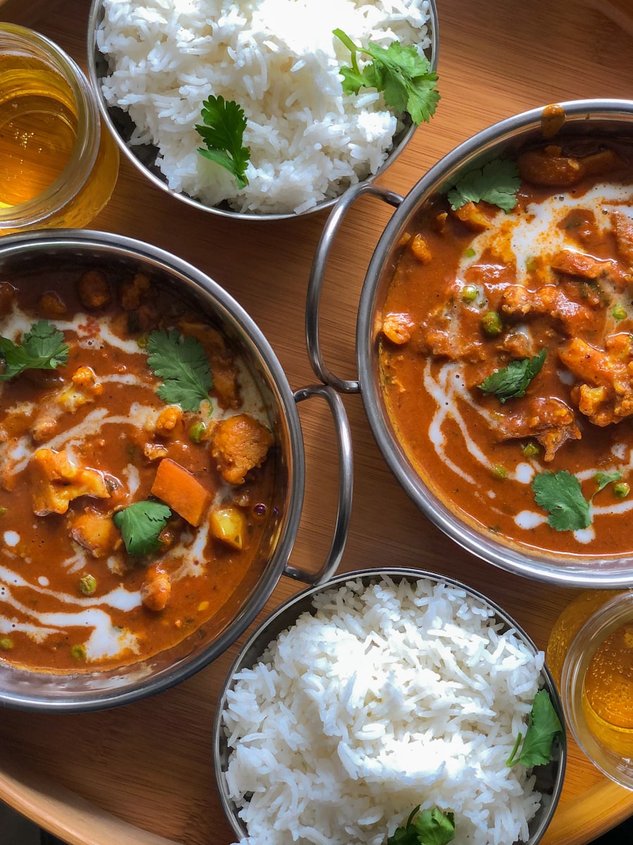 Curries and steamed rice in steel bowls